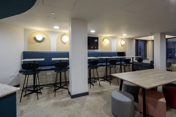 a communal area with tables and chairs in a room with white walls and blue booths