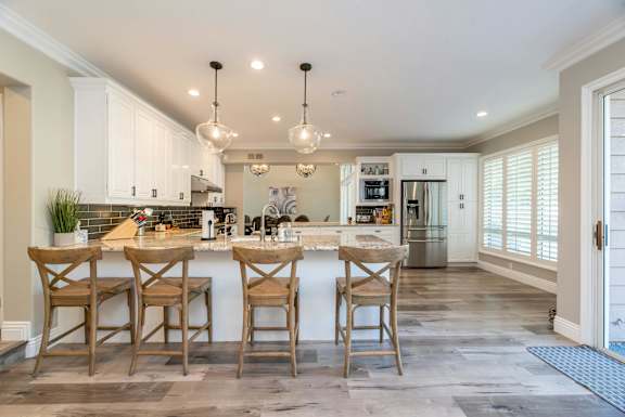 A kitchen with a white counter top and wooden chairs.