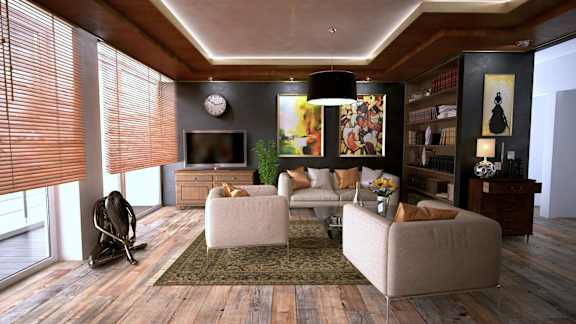 A living room with a grey sofa, a white armchair, a chair, a television, a clock, a potted plant, a rug, and a bookshelf.