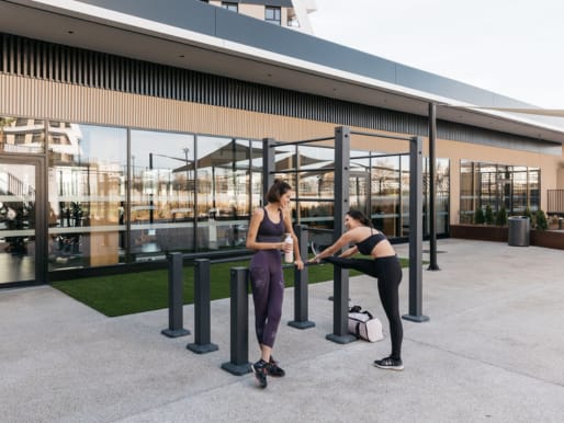 two women stretching at a railing outside of a building