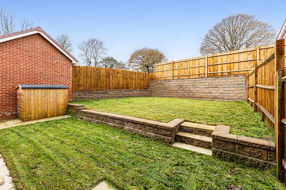 A backyard with a wooden fence and a brick building.