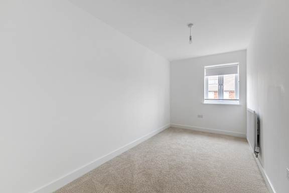 A room with a carpeted floor and a window.