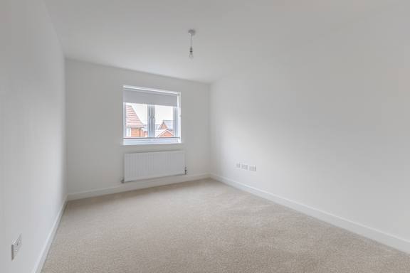 A white room with a window and a radiator on the wall.