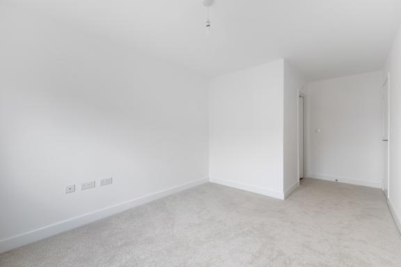 A white room with a carpeted floor and a door.