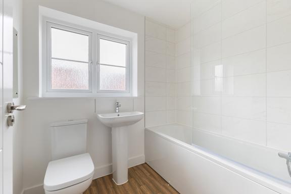 A white bathroom with a toilet, sink, and tub.