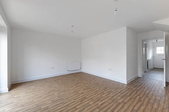 A room with wooden flooring and white walls.