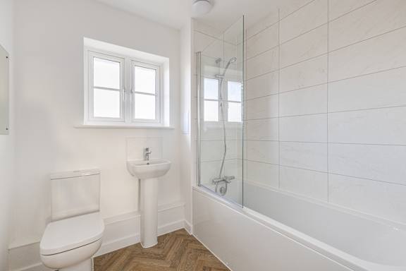 A white bathroom with a toilet, sink, and bathtub.