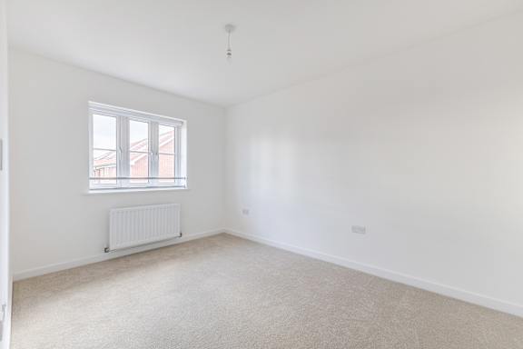A white room with a window and a radiator on the floor.