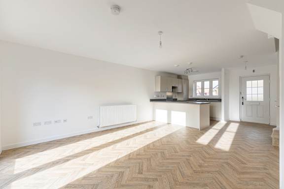 A room with wooden flooring and white walls.