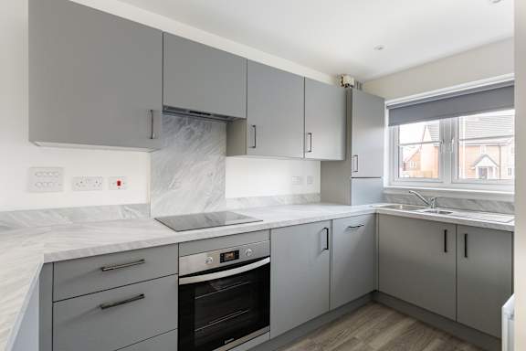 A kitchen with grey cabinets and a white marble countertop.