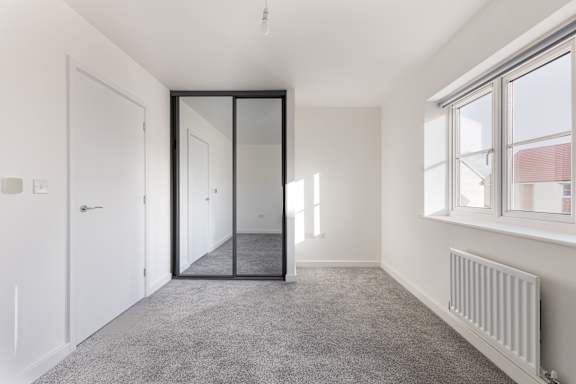 A room with a grey carpet and a white door.