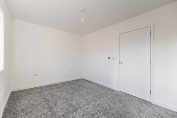 A room with a grey carpet and white walls.