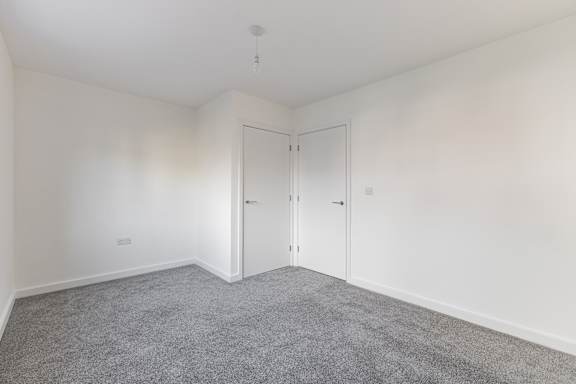 A room with white walls and grey carpet.