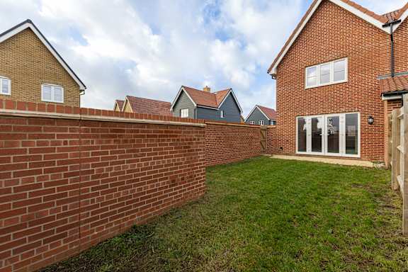 A red brick wall with a green lawn in front.
