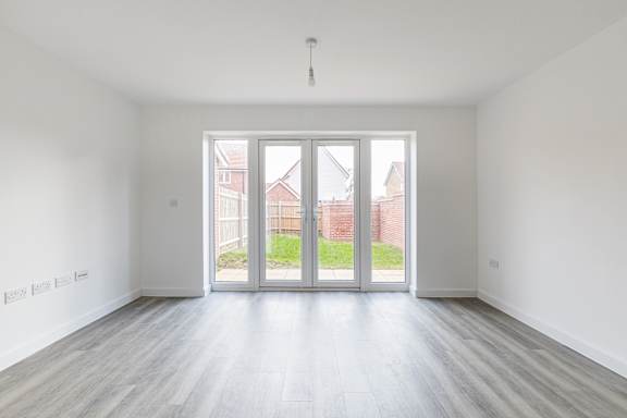 A room with a white wall and a wooden floor with a glass door.