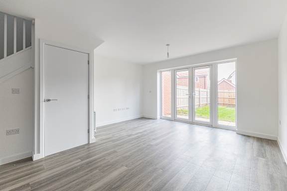 A room with a white door and a window with a view of a red building outside.