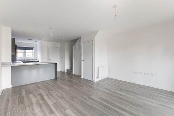 A spacious room with wooden flooring and white walls.