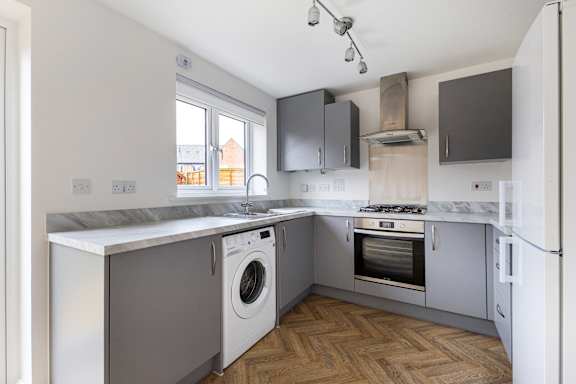 A kitchen with a washing machine and a fridge.