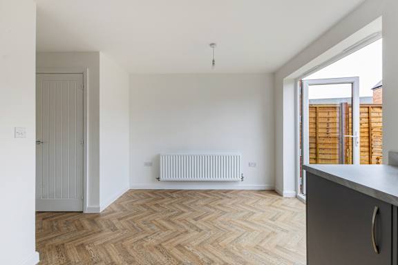 A room with a wooden floor and a white ceiling with a radiator.
