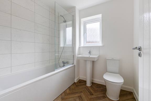 A white bathroom with a toilet, sink, and bathtub.