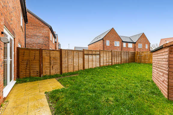A backyard with a wooden fence and a brick house.