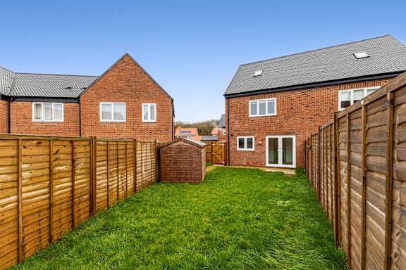 A backyard with a wooden fence and a green lawn.