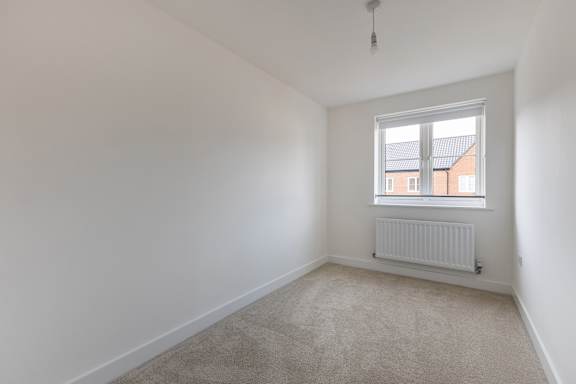A room with a window and a radiator on the floor.
