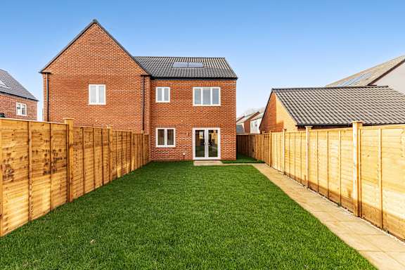A red brick house with a wooden fence and a green lawn.