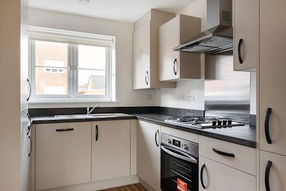 A modern kitchen with white cabinets and black countertops.