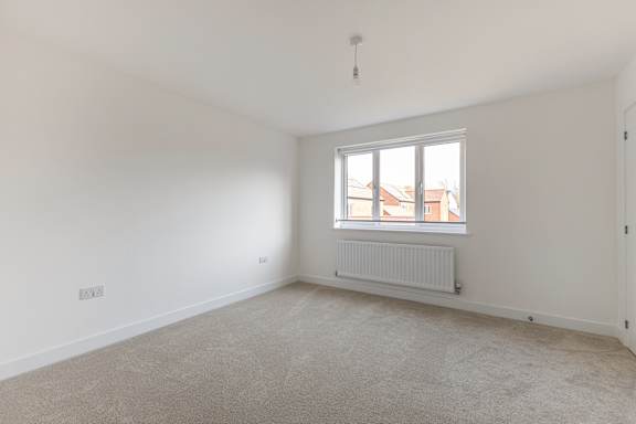 A room with a window and a radiator on the floor.