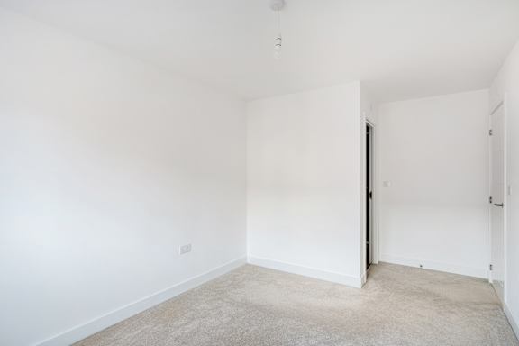 A white room with a carpeted floor and a door on the right.