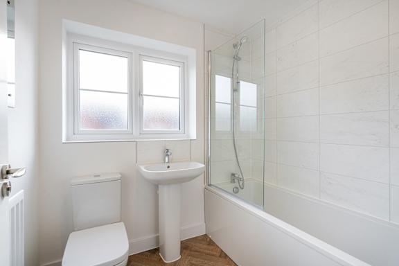 A white bathroom with a toilet, sink, and bathtub.