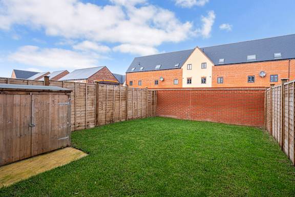 A backyard with a wooden fence and a green lawn.
