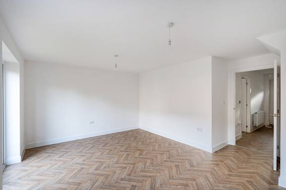 A room with a herringbone patterned floor and white walls.