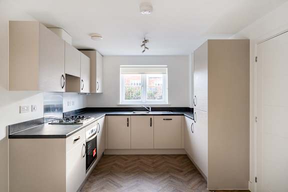 A kitchen with white cabinets and a black countertop.