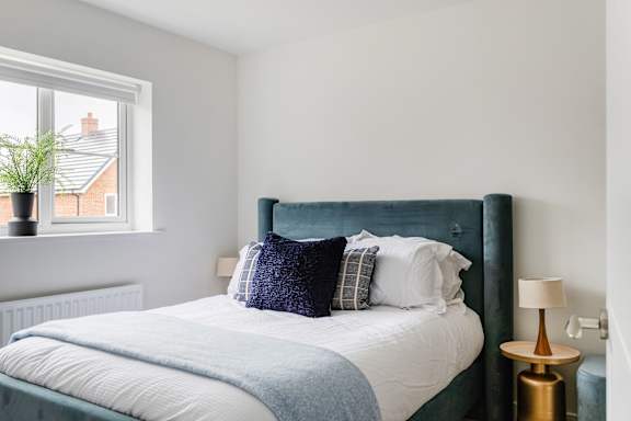 A bed with a white comforter and a blue throw pillow.