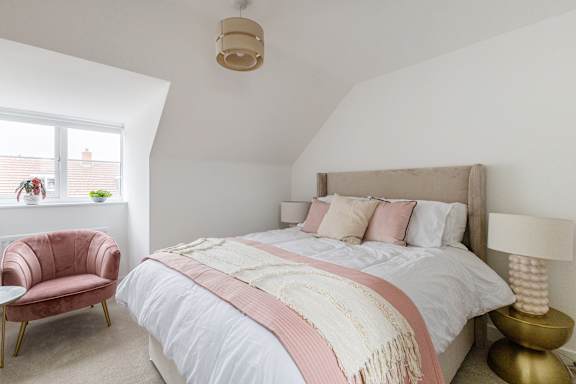 A bedroom with a bed, chair, and lamp.