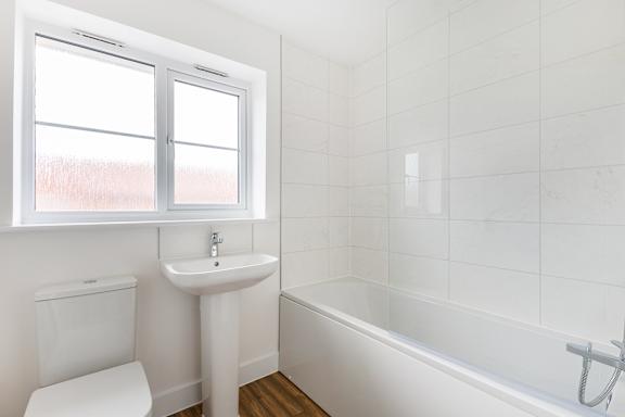 A white bathroom with a toilet, sink, and bathtub.