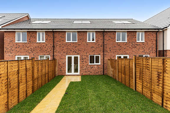 A red brick house with a wooden fence and a green lawn.