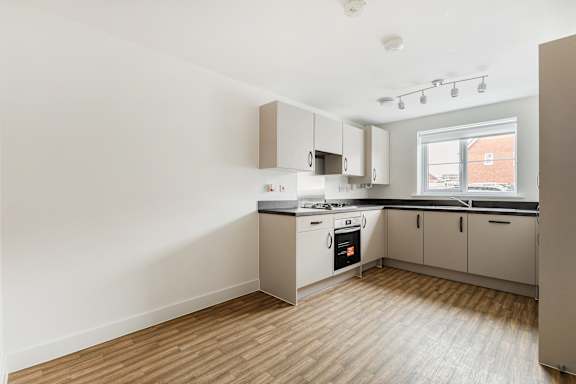 A kitchen with white cabinets and a window.