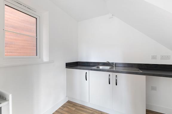 A kitchen with white cabinets and a black countertop.