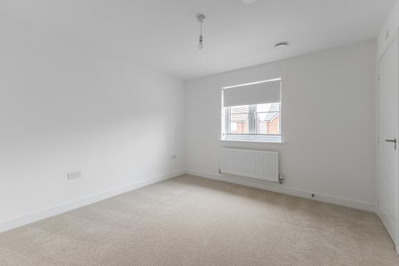 A white room with a window and a radiator on the floor.