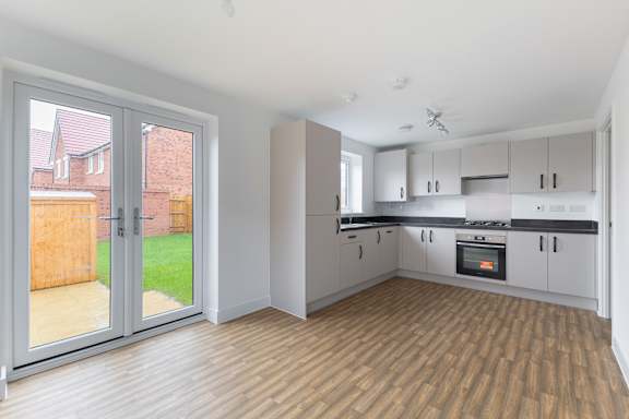 A kitchen with white cabinets and a wooden floor.