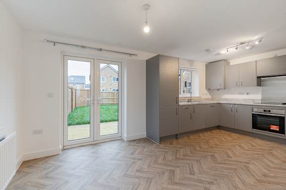 A kitchen with a wooden floor and white walls.