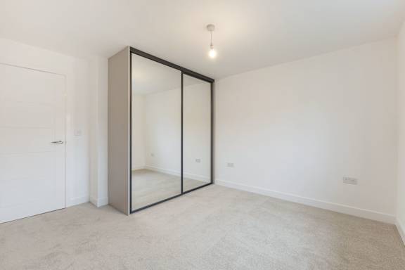 A room with a white door and a large mirror on the wall.