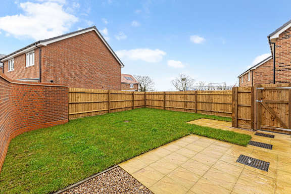 A backyard with a brick house, wooden fence, and a patio.