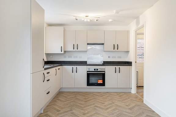 A kitchen with white cabinets and a black countertop.