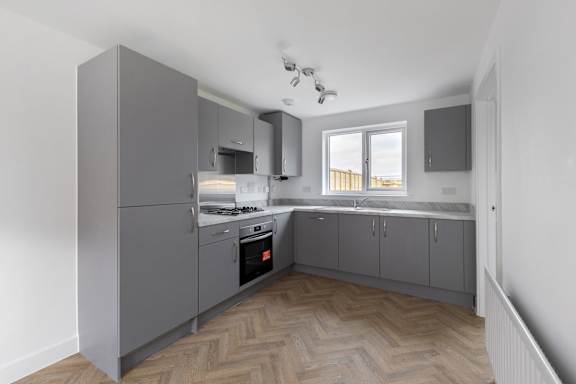 A kitchen with a grey cabinetry and a window.