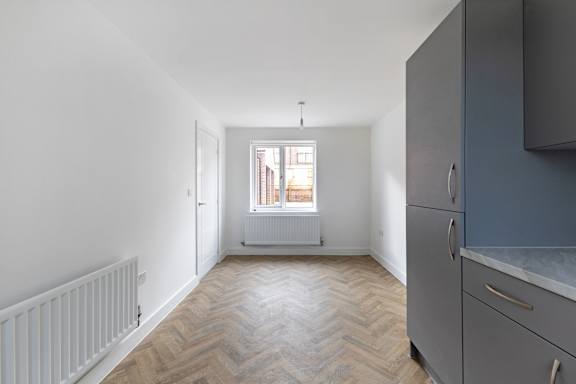 A kitchen with a white radiator and wooden flooring.