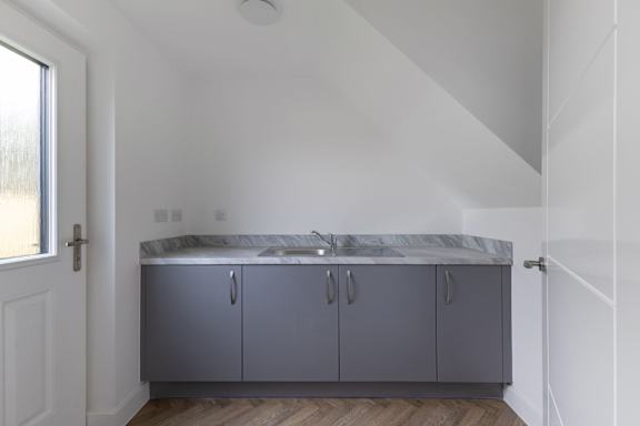 A kitchen with grey cabinets and a marble countertop.